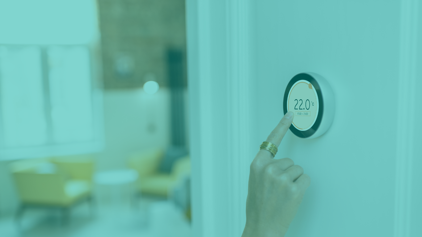 Image of a smart thermostat on a wall, with a person's hand adjusting the temperature, with a blue filter